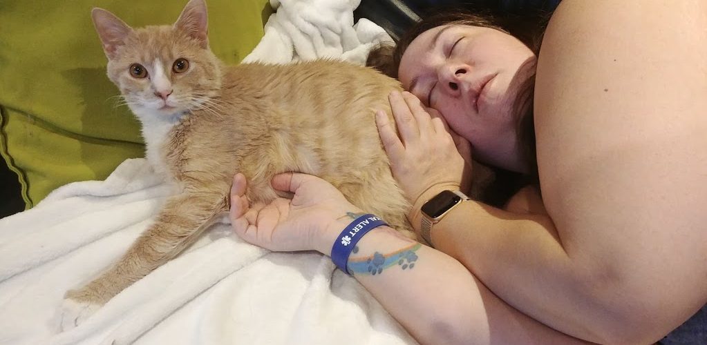 Annie-Danielle couchée la tête sur un chat orange