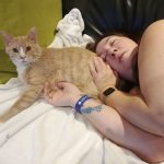 Annie-Danielle couchée la tête sur un chat orange
