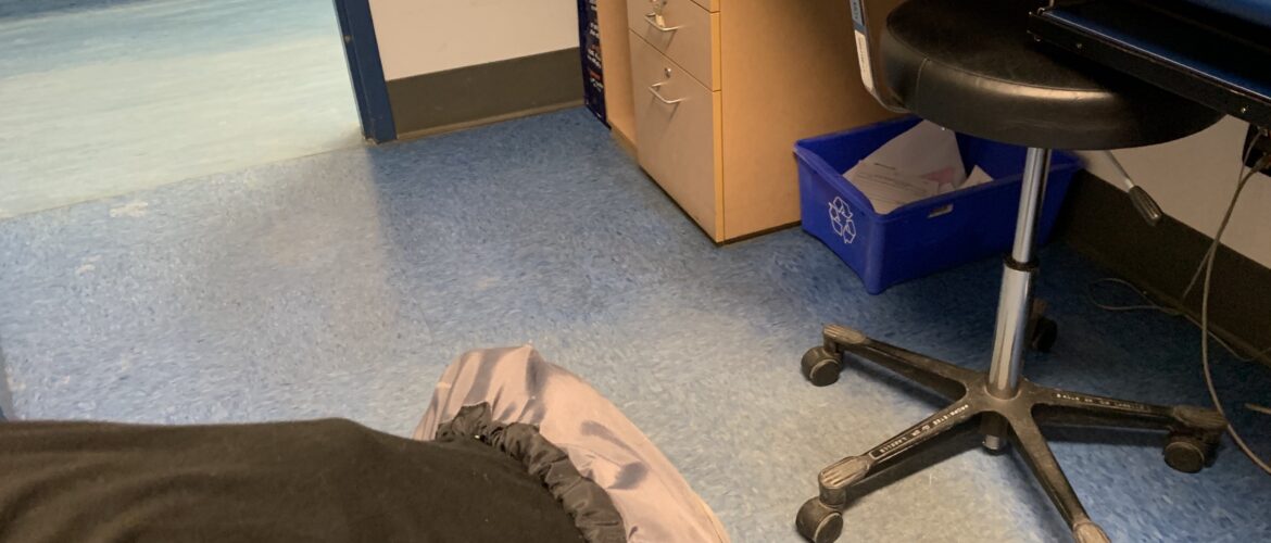 Salle d'examen avec chaise de bureau et une jambe où on voit un protège-botte sur le pied