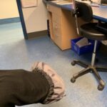 Salle d'examen avec chaise de bureau et une jambe où on voit un protège-botte sur le pied
